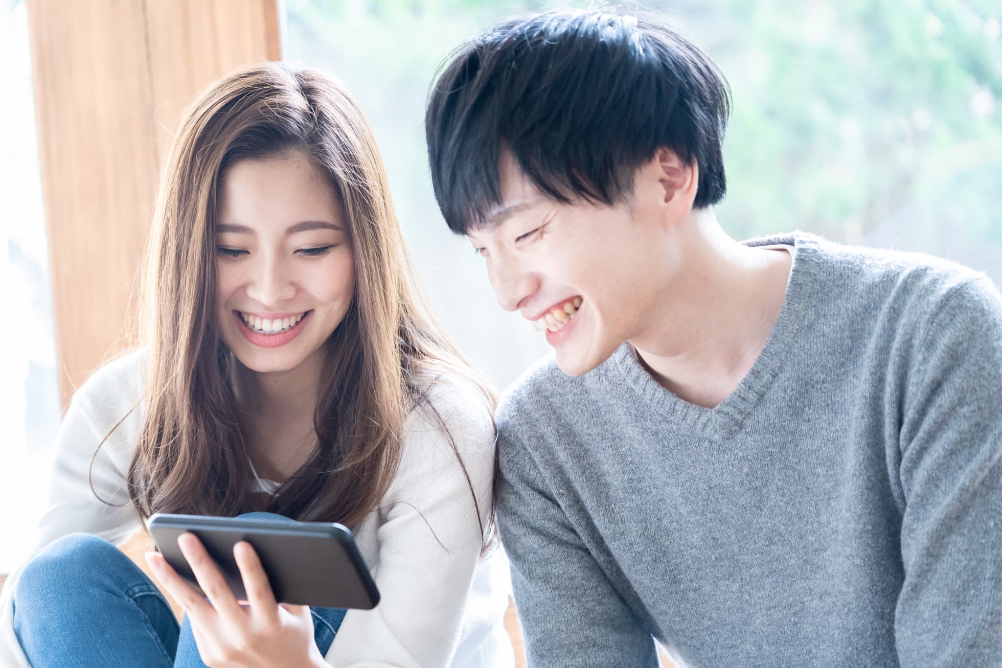 ２人でスマホを見ている笑顔のカップル