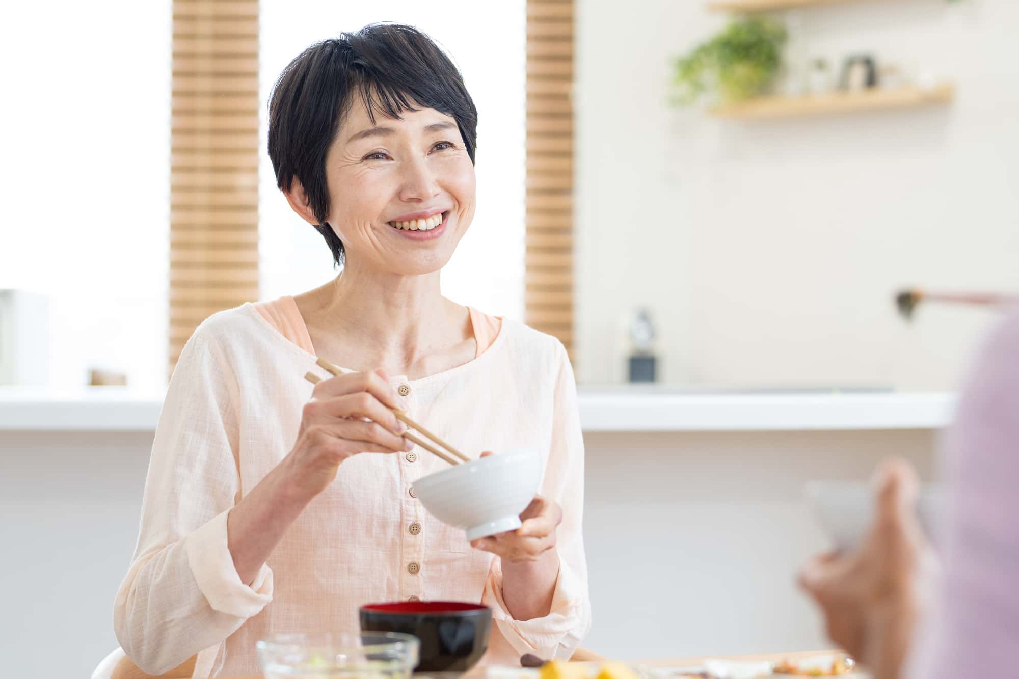 インプラント治療のやり直しを完了して食事を楽しむ女性