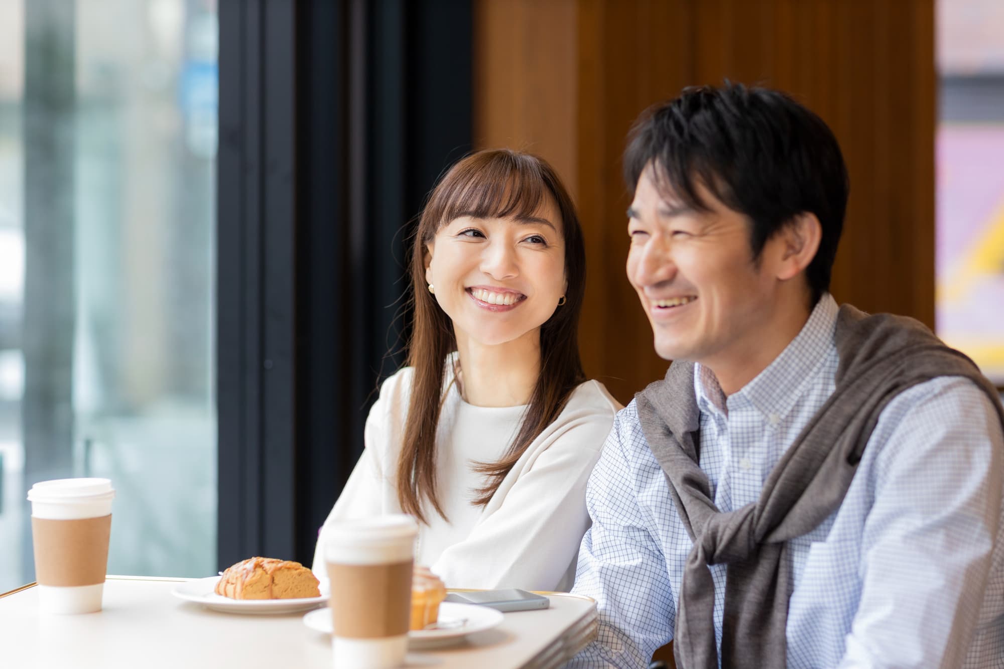 日頃からの虫歯予防で健康な歯を維持した男女がカフェで楽しく会話しているイメージ